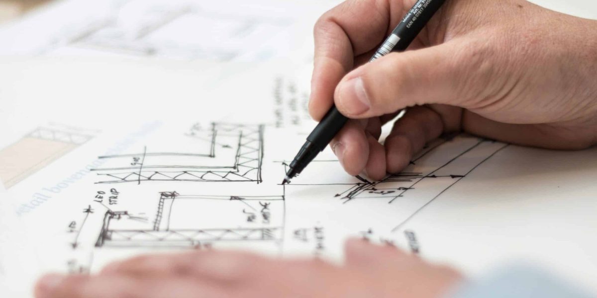 Close-up of hand drawing intricate technical designs on blueprint with pen, ideal for engineering or architecture themes.